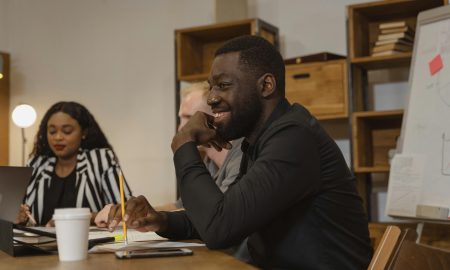 A diverse group of professionals in an office meeting, sharing ideas and smiling.